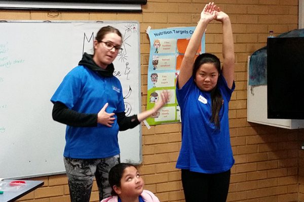 Teacher showing kids how to stretch. Link displays a larger version of the image.